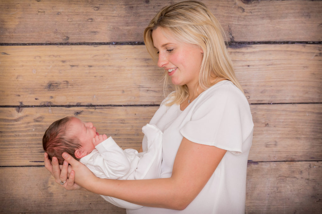 A new mum cradles her beautiful newborn baby for a professional photoshoot