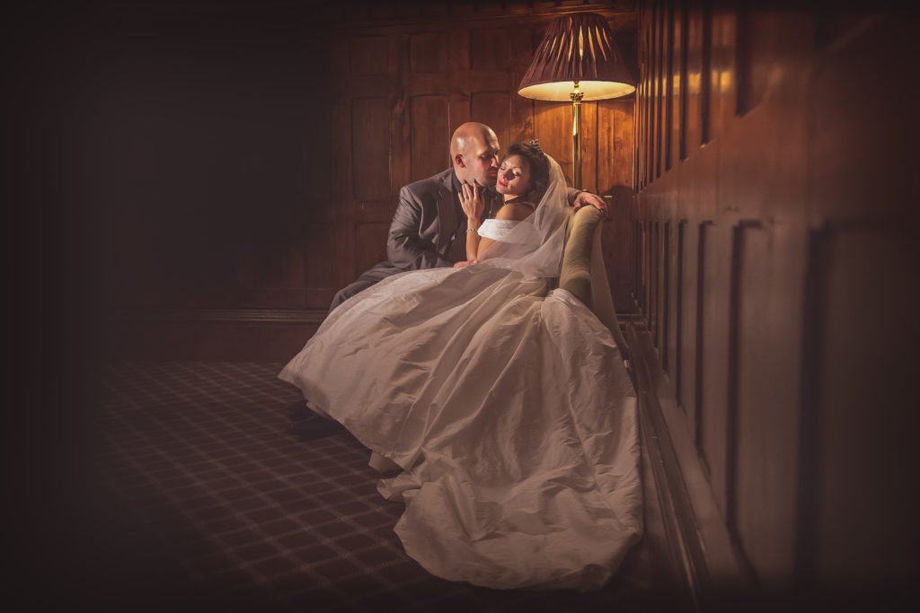 Glamourous photo of a bride and groom cuddling in soft lighting indoors by Sarah Hargreaves of Sugar Photography