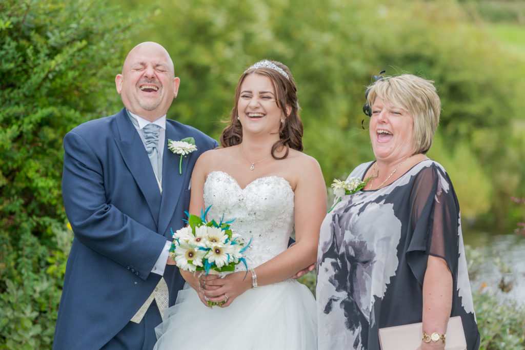 Candid photo. Wedding photographer West Yorkshire. A bride and her parents laugh during a summertime wedding in beautiful Yorkshire.