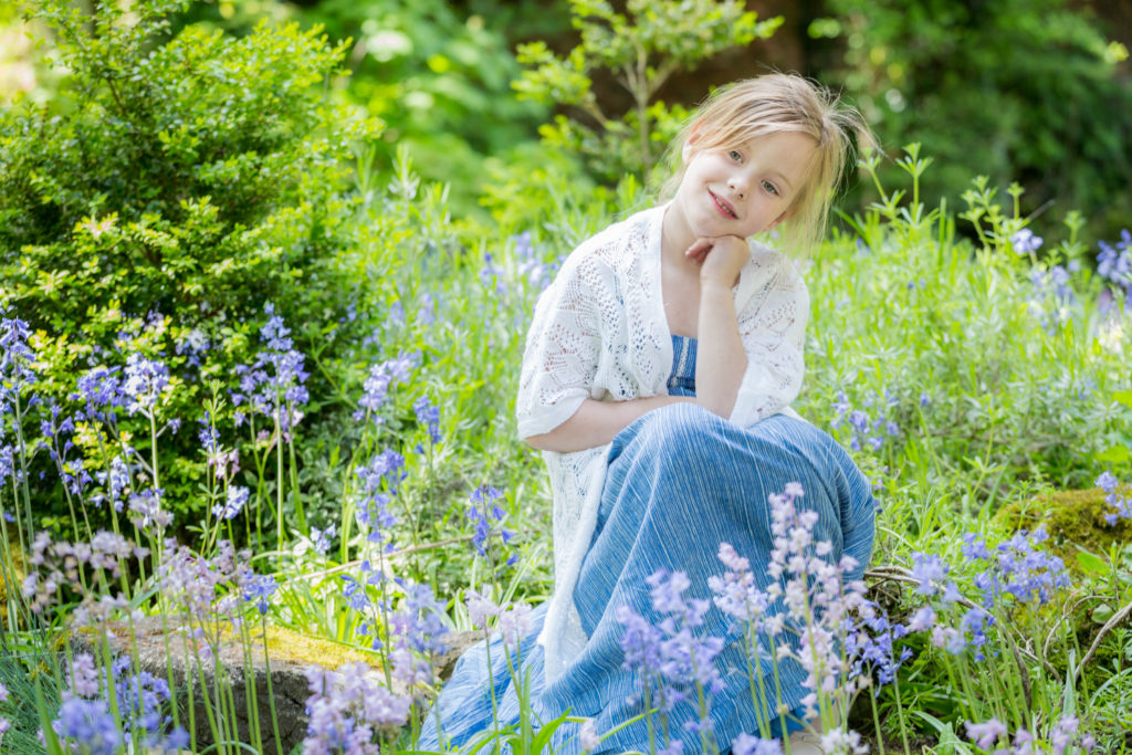 A girl sits in a patch of bluebells