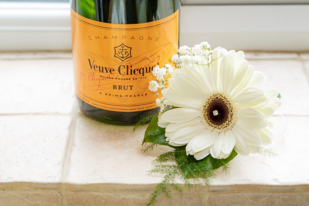 Champagne bottle and wedding buttonhole featuring a large white flower