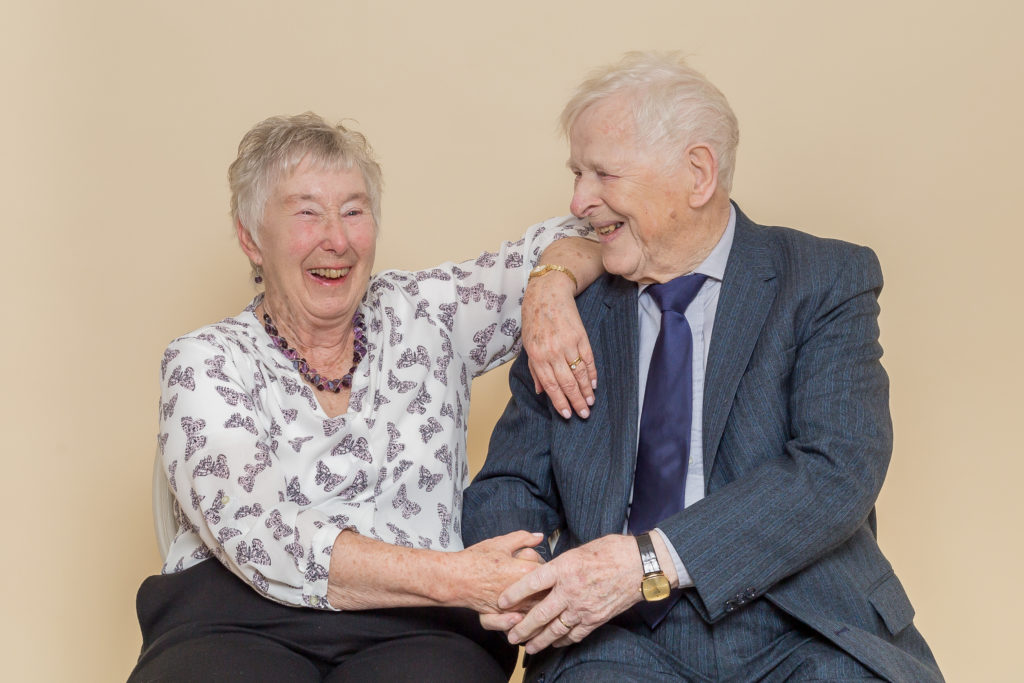 An elderly couple smile and laugh during a studio photo shoot at Sugar Photography in Horbury, West Yorkshire