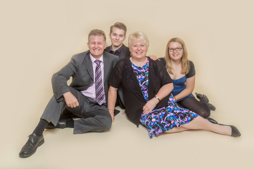 Formal studio photoshoot featuring a family dressed smartly against a golden backdrop.