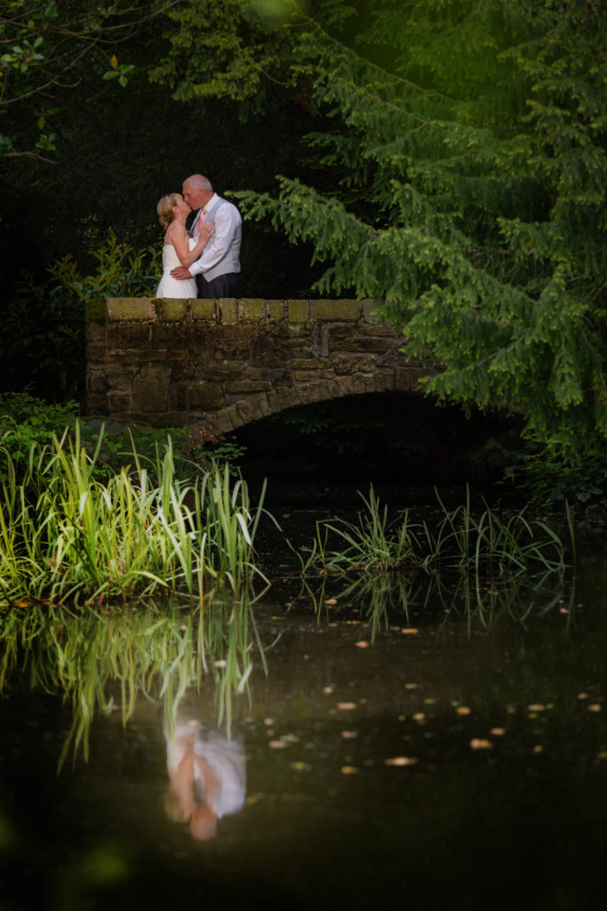 Bride and groom kissing on a bridge